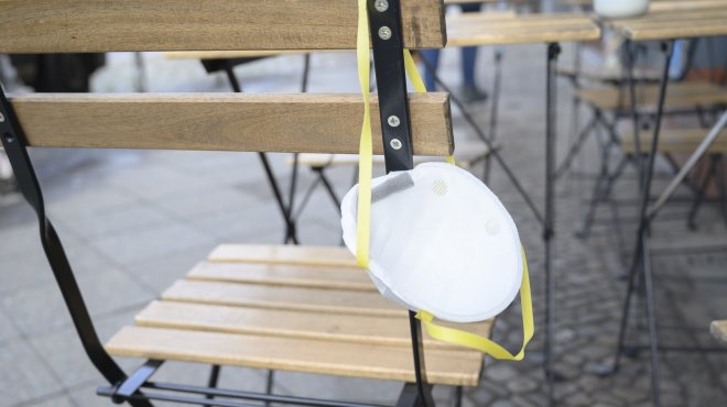 Atemschutzmaske hängt über leerem Stul vor einem Restaurant
