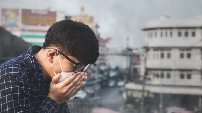 Chinesischer Mann hustet in Atemmaske