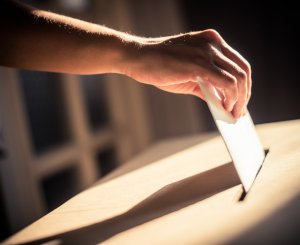 Hand wirft Stimmzettel ein