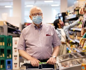 Mann mit Atemmaske wartet in Einkaufsladen