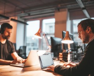 Zwei Männer sitzen sich gegenüber an Tablets und arbeiten